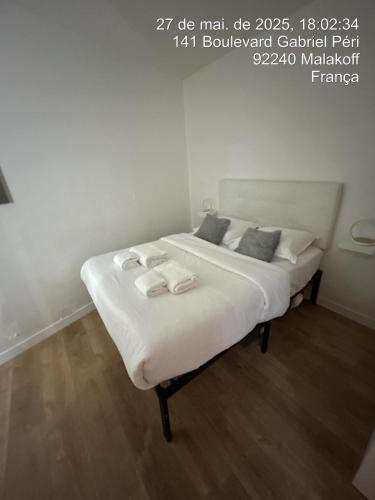un lit avec des draps blancs et des oreillers dans une chambre dans l'établissement Paris Malakoff Garden Apartments, à Malakoff