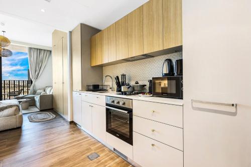 a kitchen with white cabinets and a microwave at FIRST CLASS Studio Unwind in Style in Dubai