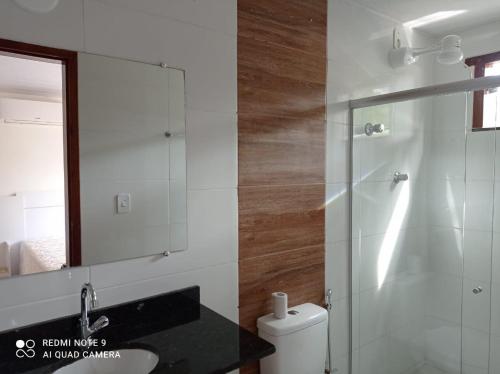 a bathroom with a sink and a mirror and a toilet at Bangalô 7b Praia de Guaratiba in Prado