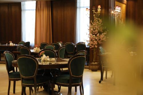 a dining room with a table and chairs and flowers at La Roche Hotel in Erbil