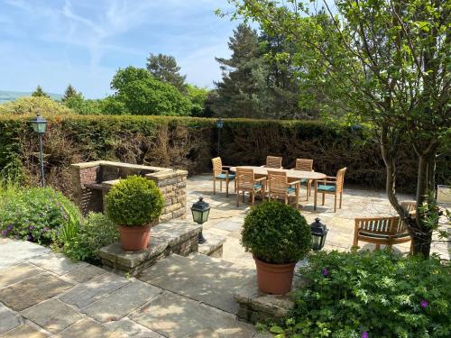 a patio with a table and chairs in a garden at Greenacres Hall in Disley