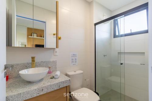 a bathroom with a sink and a toilet and a glass shower at Estadia tranquila e completa em prédio com piscina – VPD in Florianópolis