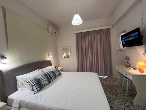a bedroom with a bed and a desk and a television at Nikos Studios in Keri
