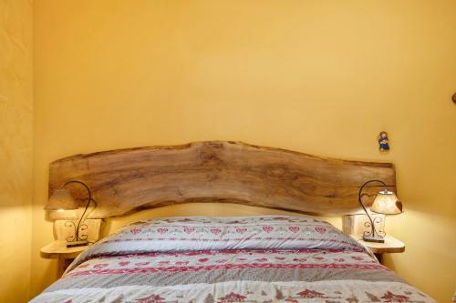 a bedroom with a wooden headboard and two lamps at La Vieille Cloche in Saint-Rhémy-en-bosses