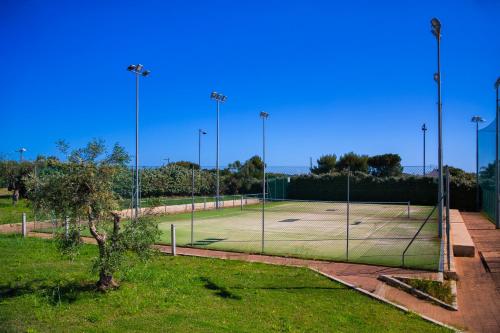 a tennis court with a net in a field at Cala Ponte, a Tribute Portfolio Hotel in Polignano a Mare