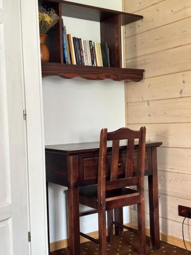 a wooden table with a chair and a book shelf at Leśne PoBudki in Białowieża