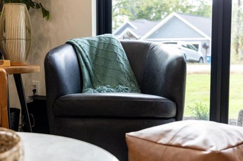 a black leather chair with a green blanket on it at Lookout Chalet NEW Build huge Party Deck Hot Tub and Trail Access in Bella Vista
