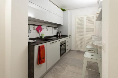 a white kitchen with white cabinets and a stool at Il Nido Nella Rocca in Porto Ercole