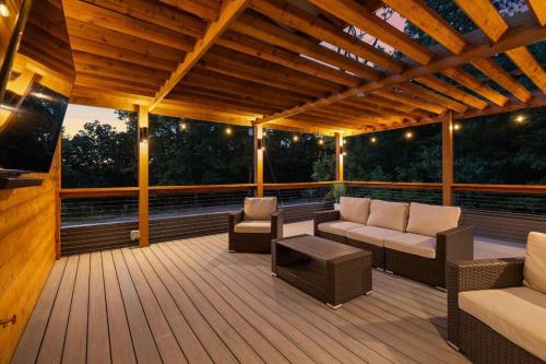 a wooden deck with a couch and chairs on it at Lookout Chalet NEW Build huge Party Deck Hot Tub and Trail Access in Bella Vista