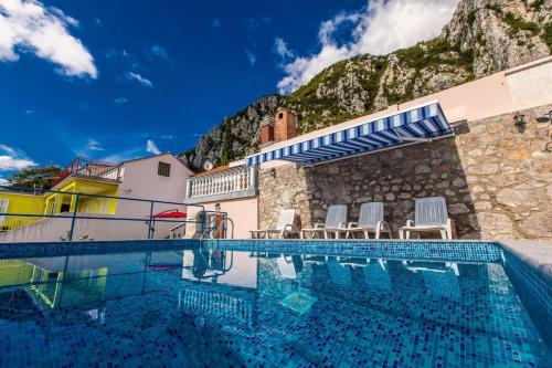 una piscina con sillas y una montaña en Poolhouse Wowox, en Grižane