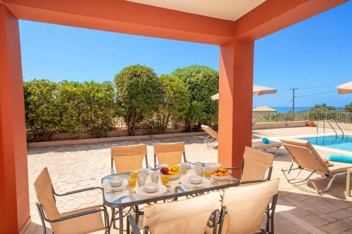 a table and chairs on a patio with a pool at Villa Provenzo by Villa Plus in Lourdhata