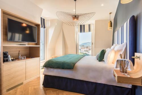 a bedroom with a large bed and a television at MADISON Saint Jean de Luz - Handwritten Collection in Saint-Jean-de-Luz