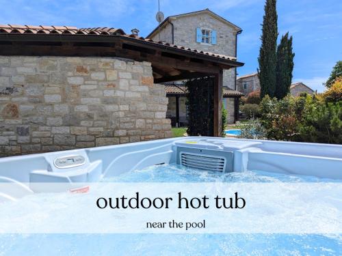 an outdoor hot tub next to a house at Villa Paolina with hot tub in Višnjan