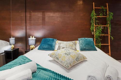 une chambre avec un lit blanc avec des oreillers bleus dans l'établissement Village Naturiste R4N - Le Tikanah Port Nature, au Cap d'Agde