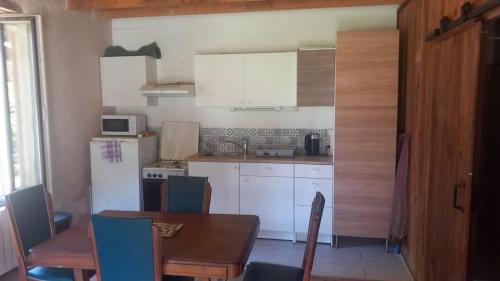 une cuisine avec des armoires blanches et une table avec des chaises dans l'établissement Ferme La Petite Verte, à Saint-Pierre-de-Frugie