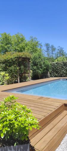 une piscine avec une terrasse en bois et quelques plantes dans l'établissement Maison Balaguera, à Saint-Jean-de-Marsacq