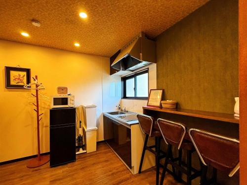 a kitchen with a sink and a counter with chairs at 星宿川-楓の宿201 in Osaka
