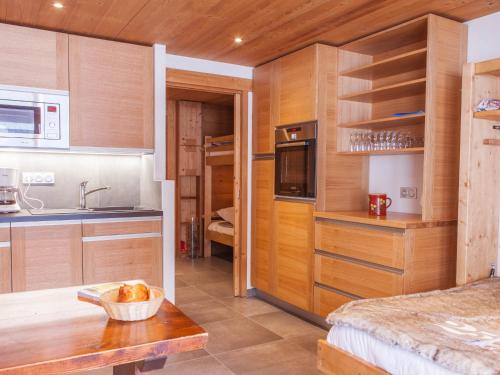 Elle comprend une petite cuisine avec des placards en bois et un évier. dans l'établissement Studio montagnard avec balcon, vue montagnes et accès bien-être - FR-1-467-38, au Grand-Bornand