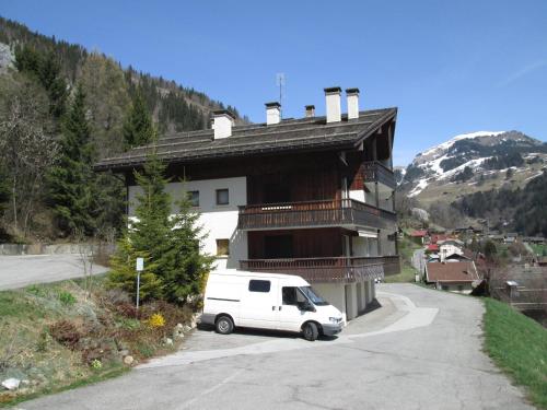 une camionnette blanche garée devant un immeuble dans l'établissement Charmant studio montagnard avec accès spa, proche centre et pistes, parking inclus - Le Grand-Bornand Village - FR-1-467-28, au Grand-Bornand