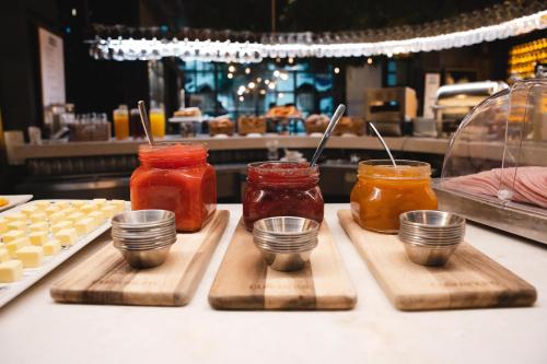 Un mostrador con tres frascos de miel sobre tablas de cortar. en The Central House Granada Elvira, en Granada