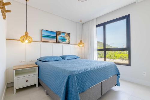 a bedroom with a blue bed and a window at Apartamento alto padrão com piscina em Bombinhas in Bombinhas