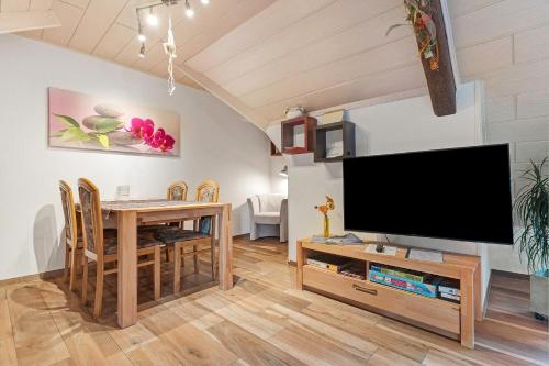 a living room with a television and a table with chairs at Altes Forsthaus - Fewo Bianca in Bad Peterstal-Griesbach