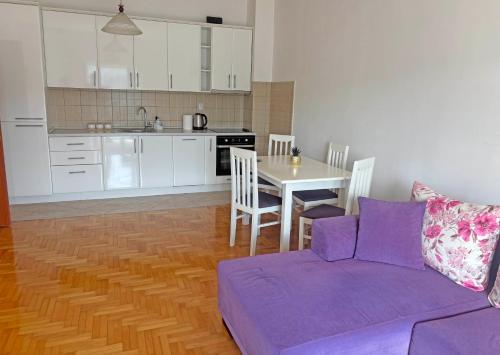 a living room with a purple couch and a kitchen at Topla Heat Apartman in Herceg-Novi