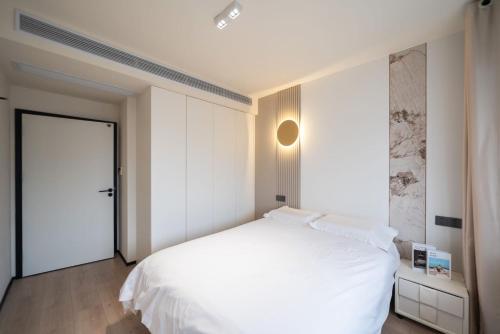 a white bedroom with a white bed and a door at Pure Home-Near the Bund enjoys the beautiful scenery of the Bund 3-bedhome close to Yuyuan Garden Huaihai Road and Nanjing Road Pedestrian Street in Shanghai
