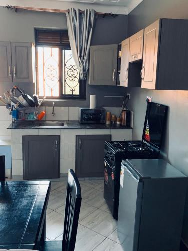 a kitchen with black and white cabinets and a stove at Keaden-homes in Kampala