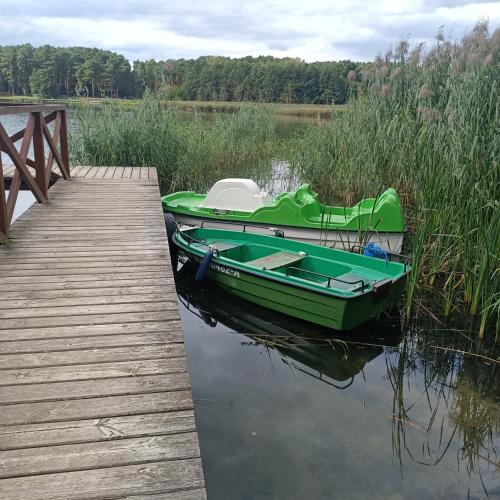 a green boat is docked next to a dock at Domek02 Ośrodek Wypoczynkowy Joanna Wojnowo Lubuskie in Kargowa