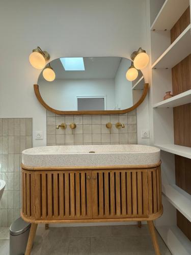 une salle de bain avec un lavabo et un miroir dans l'établissement Villa Palmeraie - Piscine, à Lagord
