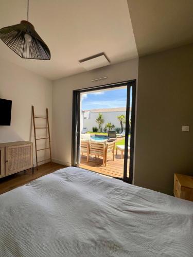 - une chambre avec un lit et une vue sur une terrasse dans l'établissement Villa Palmeraie - Piscine, à Lagord