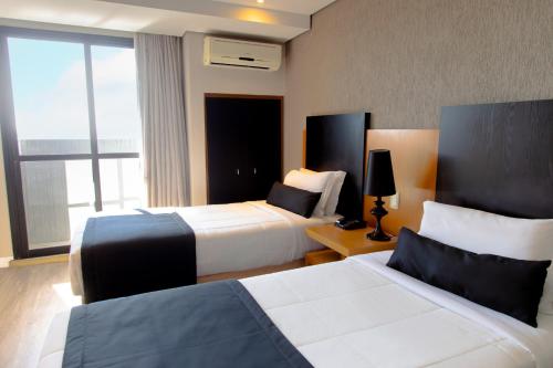 a hotel room with two beds and a window at Slaviero Hotel Curitiba Batel in Curitiba