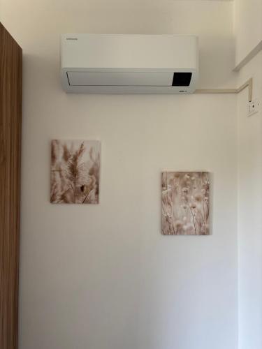 three pictures hanging on a white wall with a light at Casa Maria in Serra Riccò