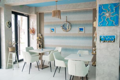 Un comedor con mesas blancas y sillas blancas. en Brizo Boutique Hotel, en Mamaia