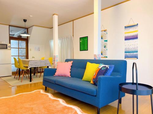 a living room with a blue couch with colorful pillows at Stay Like a Local Hiroshima Hiroshima Station Entire House 1-6 ppl in Hiroshima