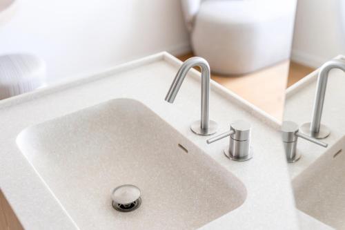 a white sink with three faucets on a counter at Hotel Bommelje in Domburg