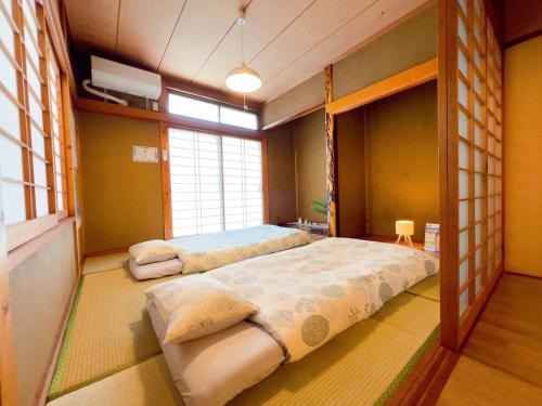 a bedroom with two beds and a window at Stay Like a Local Hiroshima Hiroshima Station Entire House 1-6 ppl in Hiroshima