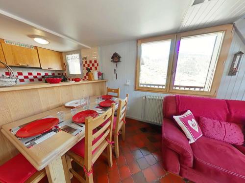 un salon avec une table et un canapé rouge dans l'établissement Appartement 3 pièces, 7 couchages, Le Grand-Bornand - FR-1-241-203, au Grand-Bornand