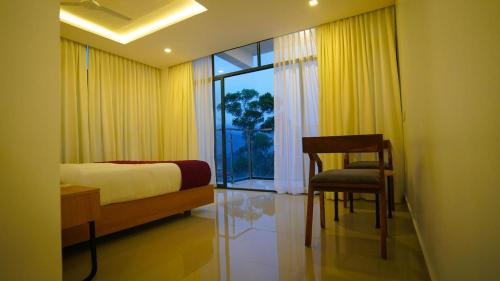 a bedroom with a bed and a chair and a window at Sunrise Munnar in Anachal