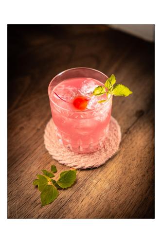a glass of pink drink with a cherry on a table at Seehotel Schwert in Gersau