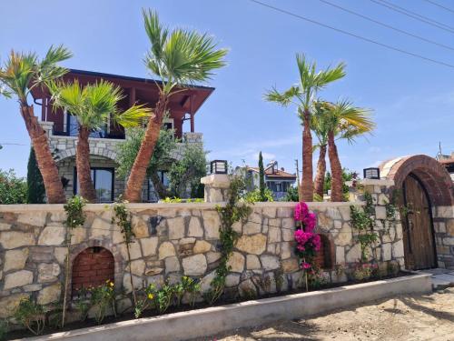 a retaining wall with palm trees in front of a house at Velder House Urla in Urla