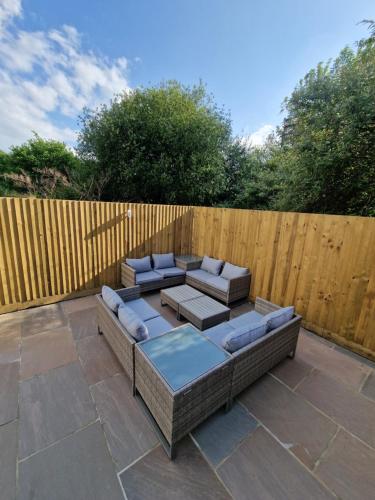a patio with two couches and a wooden fence at Stunning Modern Riverside Cottage in Aberdulais