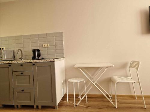 a kitchen with a counter and two chairs and a table at Studija29 in Klaipėda