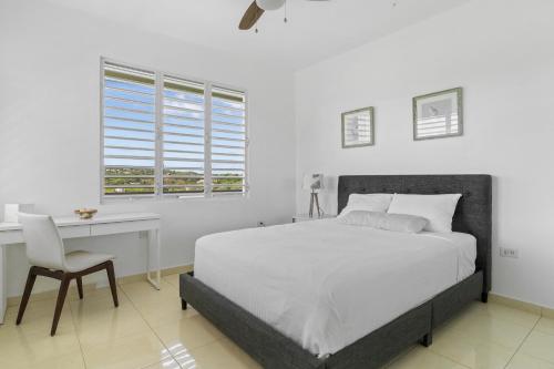 a bedroom with a bed and a desk and a window at Tropical Paradise in Rincon in Aguada