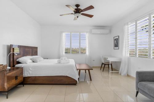a white bedroom with a bed and a ceiling fan at Tropical Paradise in Rincon in Aguada
