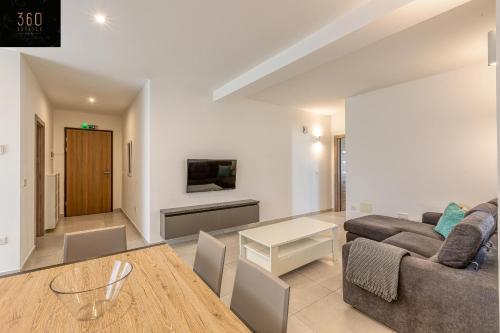 a living room with a couch and a table at Stunning 2BR penthouse with harbour view & BBQ by 360 Estates in Tal-Pietà