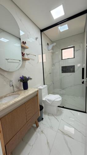 a bathroom with a toilet and a glass shower at Apto Flor de Romã - 2 Quartos, Apto todo climatizado, à 150m do Parque Termal! in Piratuba