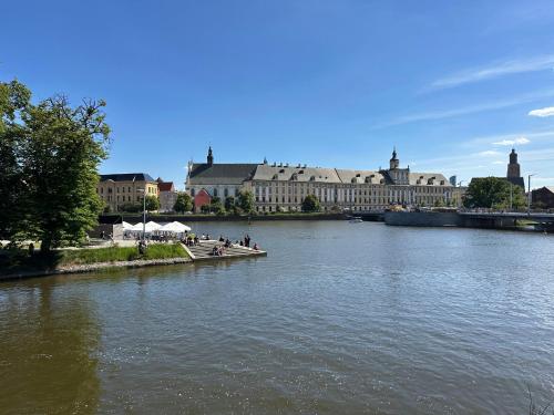 Boulevard Drobnera IV - Apartament nad Odrą - Rynek في فروتسواف: اطلاله على نهر وبه مباني في الخلف
