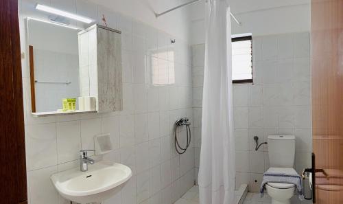 a white bathroom with a sink and a toilet at Guesthouse Lykourgos in Mavrommátion